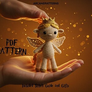 Peut inclure: Une poupée centaure au crochet avec une couronne et des ailes, tenue dans des mains en coupe. La poupée est beige avec des accents dorés. Le texte sur l'image indique "PDF PATTERN" et "Included Stitch Guide and Gifts."
