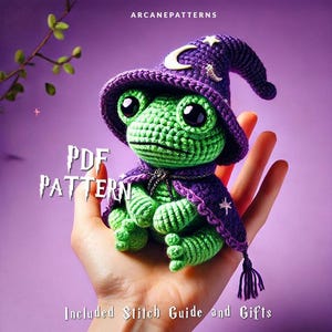 Może przedstawiać: Zielona dziana żaba w fioletowym kapeluszu czarownicy z gwiazdami i rosnącym księżycem. Żaba trzyma fioletową różdżkę. Tekst "PDF PATTERN" jest napisany na czarnym tle białym kolorem. Tekst "Included Stitch Guide and Gifts" jest napisany na czarnym tle białym kolorem.