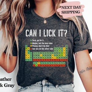 May include: Heather dark gray t-shirt with the text "CAN I LICK IT?" and a periodic table of elements. The shirt also includes the phrases "Sure, go for it", "Maybe, not the best idea", "Please, don't do that", and "See you on the other side".