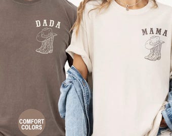 May include: Espresso-colored and ivory-colored t-shirts with the words "DADA" and "MAMA" printed above a cowboy hat and boot design. The shirts are part of the Comfort Colors collection.
