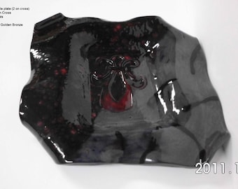 May include: A black ceramic plate with a red and black cross design. The plate has a glossy finish and is decorated with a red halo around the cross. The plate is signed with the date "2011.10.6".