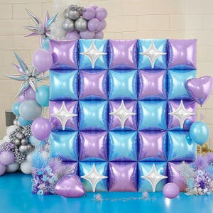 Pu&ograve; includere: Un fondale decorativo con una griglia di palloncini quadrati iridescenti viola e blu, accentuati da decorazioni bianche a forma di stella. La scena comprende vari palloncini nelle tonalit&agrave; del viola, blu, argento e bianco, creando un'atmosfera festosa.