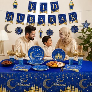 May include: A festive Eid Mubarak table setting with a blue tablecloth and matching plates, cups, and napkins. The table is set with gold cutlery and decorated with a banner that reads "Eid Mubarak". A family is seated around the table.