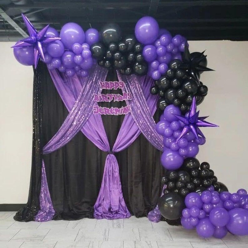 May include: A party backdrop featuring black and purple balloons, a black sequined curtain, and purple draping. The backdrop includes a sign that reads "Happy Birthday Jeremy". Star-shaped balloons and clusters of balloons are arranged to create a festive atmosphere.