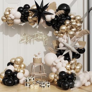 May include: A party decoration arrangement featuring a balloon arch in black, gold, and white. The arch includes star-shaped decorations and the text "Let's Party". A small cake and wrapped gifts are also present.
