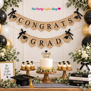 May include: A graduation party set featuring two burlap pennant banners with black text reading CONGRATS GRAD and black graduation cap icons. Includes a white cake with a gold Congrats Grad topper, cupcakes, a black mortarboard, and books.
