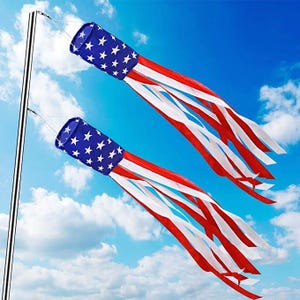 May include: Two wind socks with a patriotic design. The wind socks feature a blue cylinder with white stars and red and white stripes, resembling the American flag. They are suspended from a silver pole against a blue sky with clouds.