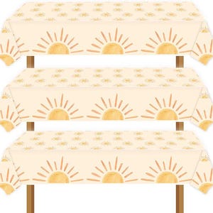 May include: Three white tablecloths with a repeating pattern of stylized suns in shades of orange and yellow. The tablecloths are layered on top of each other, with the top tablecloth slightly overlapping the bottom two.