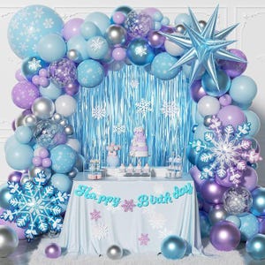 May include: A festive birthday party scene with a light blue and purple color scheme. Balloons, snowflake decorations, and a cake create a winter wonderland theme. A banner reads "Happy Birthday."