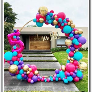 Puede incluir: Un arco de globos vibrante en forma de semic&iacute;rculo, con una mezcla de globos rosas, turquesas, morados y dorados. Un gran globo rosa con el n&uacute;mero 5 est&aacute; a la izquierda. El arco tiene el nombre "Ana Pili" en letras doradas.