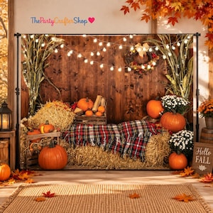 May include: A photography backdrop featuring a rustic wooden wall, hay bales, and a plaid blanket. The scene includes orange pumpkins, white chrysanthemums, corn stalks, and a string of warm white fairy lights. Text reads ThePartyCrafterShop.