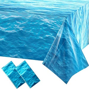 May include: A blue tablecloth and two matching placemats with a water wave design. The tablecloth is rectangular and covers a table corner. The placemats are rectangular and feature the same ocean wave pattern.