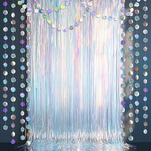 May include: Iridescent silver fringe backdrop with hanging circular garlands. The backdrop features vertical strands of shiny material, creating a shimmering effect. The garlands are made of reflective, colorful circles, adding a festive touch. Ideal for parties and events.