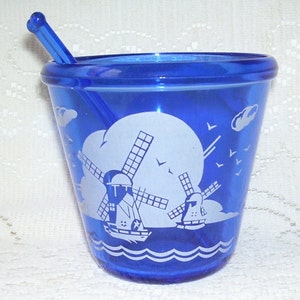 May include: Cobalt blue glass sugar bowl with a white windmill design and a matching stirrer. The bowl has a rounded bottom and a wide rim.