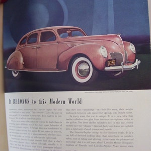 May include: A vintage, light pink, four-door sedan with whitewall tires and a chrome bumper. The car has a license plate that reads "29:427". The car is parked on a street with a blue sky in the background. The text "It BELONGS to this Modern World" is printed in black at the bottom of the image.
