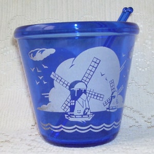 May include: Cobalt blue glass sugar bowl with a white windmill and seagull design. The bowl has a matching cobalt blue glass stirrer.