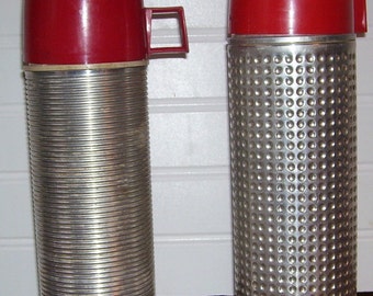 May include: Two vintage thermoses with red lids. The thermos on the left has a ribbed silver body. The thermos on the right has a silver body with a textured pattern.