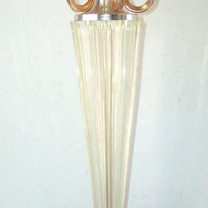 May include: A gold trophy with a clear glass base and a black base with a gold band featuring a repeating pattern of running figures. The trophy has a gold bowl on top with three gold rings.