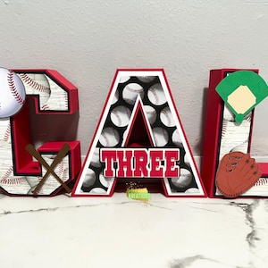 May include: Red, white, and black baseball-themed letters spelling "CAL THREE" with a baseball, bats, and a baseball glove.