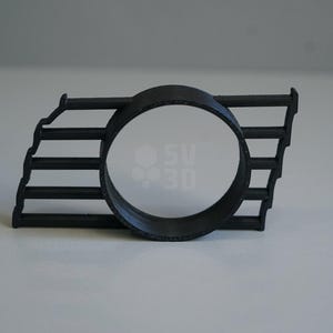 Può includere: Pezzo di auto in plastica nera con un'apertura rotonda e una serie di barre orizzontali.