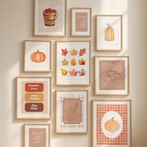 Op de afbeelding: Een galerijwandset van tien ingelijste prints met herfstthema's, waaronder een emmer met appels, pompoenen, herfstbladeren en teksten zoals Pumpkin Patch, Apple Picking, Hay Rides en I'm so glad I live in a world where there are Octobers.