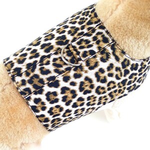 May include: A brown and black leopard print dog harness with a silver metal D-ring.