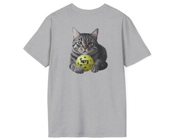 以下が含まれることがあります： 黄色のピクルボールを手にしたトラ猫のグラフィックがプリントされたグレーのTシャツ。Tシャツには「OTC Pickleball」の文字が書かれています。
