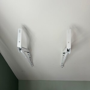 a pair of white brackets on a white ceiling