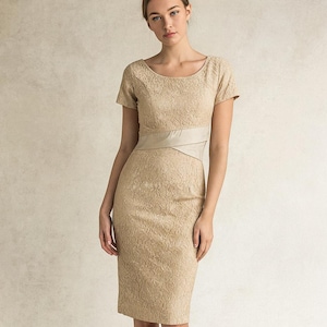 May include: A beige, knee-length dress with short sleeves and a scoop neckline. The dress features a textured, lace-like pattern and a contrasting beige band at the waist. The dress is form-fitting and suitable for formal occasions.