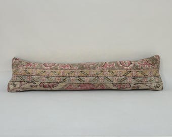 May include: A long, rectangular pillow with a colorful, floral pattern. The pillow is made of a soft, woven fabric and has a beige, pink, and brown color scheme.
