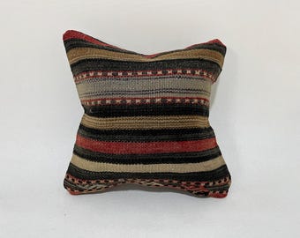 May include: A striped throw pillow with a black, red, brown, and beige color scheme. The pillow is made of a woven fabric and has a slightly textured surface.