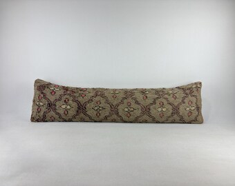 May include: A long, rectangular pillow with a patterned design. The pillow features a beige background with a repeating pattern of burgundy and pink floral-like shapes. The pillow is a decorative item.