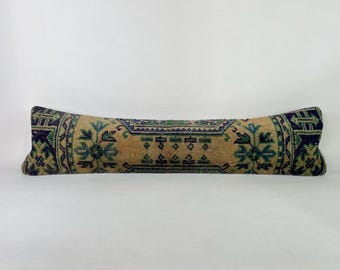 May include: A long, rectangular pillow with a beige background and a colorful geometric pattern in shades of blue, green, and brown. The pillow is made of a soft, woven fabric and is perfect for adding a touch of bohemian style to any room.