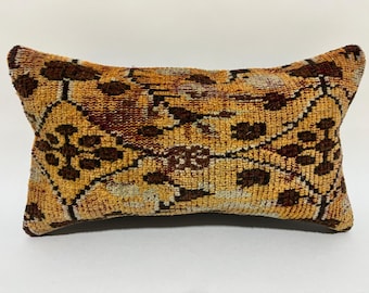 May include: A rectangular pillow with a brown, yellow, and red patterned fabric. The pillow has a floral design and is made of a soft, woven material.