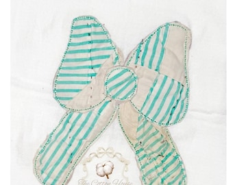 May include: A handmade fabric bow with a white background. The bow features alternating stripes of white and turquoise. The bow's edges are outlined with a dotted stitch. The text "The Cotton House Sewing and Embroidery" is at the bottom.