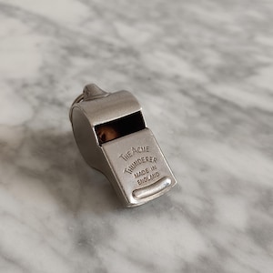 May include: Silver whistle with the inscription "The Acme Thunderer Made in England".