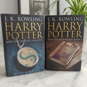 May include: Two hardcover books by J.K. Rowling titled Harry Potter and the Deathly Hallows and Harry Potter and the Half-Blood Prince. The first cover features a silver locket with green stones, while the second shows an old, worn book.