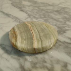 Puede incluir: Un posavasos redondo de m&aacute;rmol verde y blanco con un patr&oacute;n de remolino.