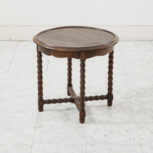 May include: A small, round, wooden side table with a dark brown finish. The table has a scalloped edge and turned legs. The table is approximately 24 inches in diameter and 24 inches tall.