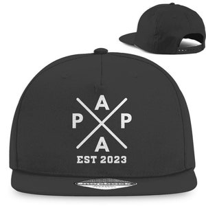 Könnte beinhalten: Schwarze Baseballkappe mit einem schwarz-weißen Logo. Das Logo ist ein Kreuz mit den Buchstaben "PAPA" und "EST 2023" darunter.