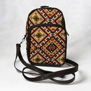May include: A small brown crossbody bag with a geometric pattern in shades of yellow, orange, red, and black. The bag has a long adjustable strap.