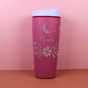 A stylish SmoothSip travel coffee cup personalized with a name, decorated with whimsical botanical accents and celestial motifs, blending cottagecore and boho vibes for a cozy, aesthetic drinkware piece.