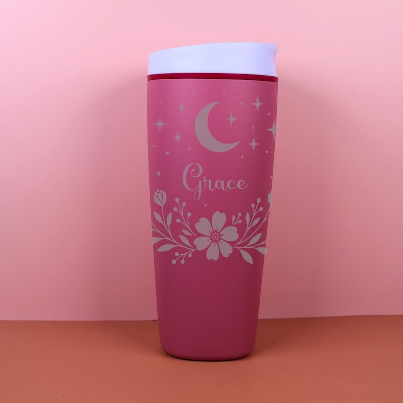 A stylish SmoothSip travel coffee cup personalized with a name, decorated with whimsical botanical accents and celestial motifs, blending cottagecore and boho vibes for a cozy, aesthetic drinkware piece.