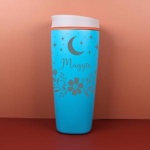 A custom floral celestial tumbler featuring a name engraving-style design, perfect as a bridesmaid proposal gift, with soft earthy tones and intricate botanical details wrapping around the cup.