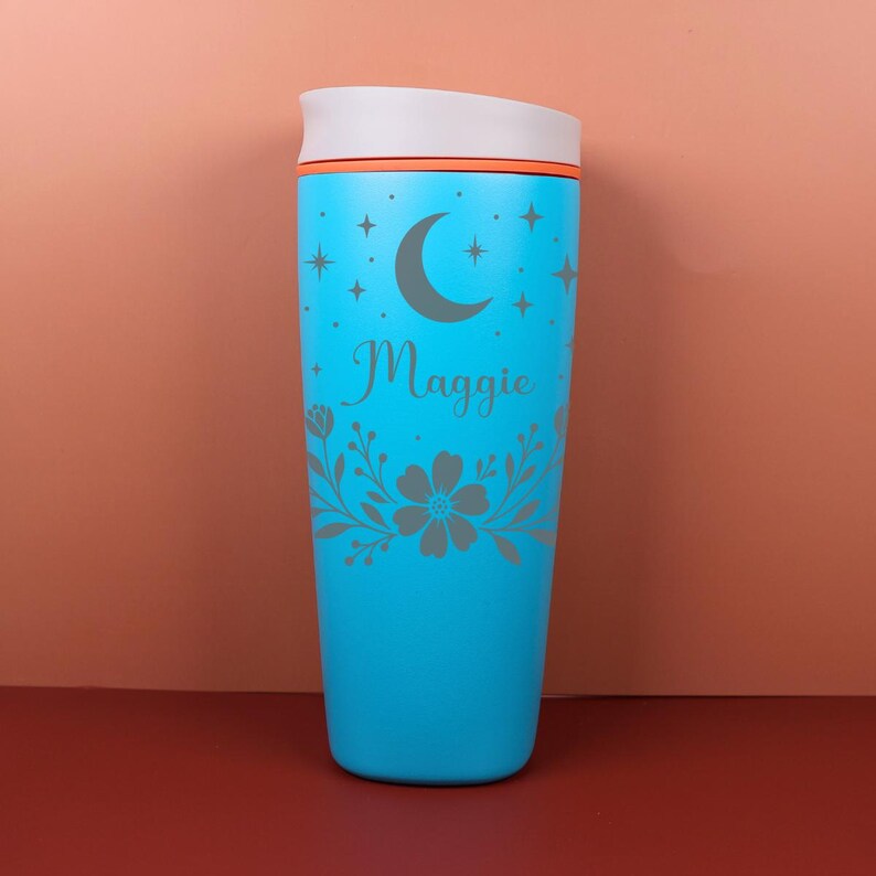 A custom floral celestial tumbler featuring a name engraving-style design, perfect as a bridesmaid proposal gift, with soft earthy tones and intricate botanical details wrapping around the cup.