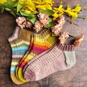May include: Three pairs of colourful striped socks in pink, blue, yellow, orange and brown. The socks are made of a soft, knitted fabric.