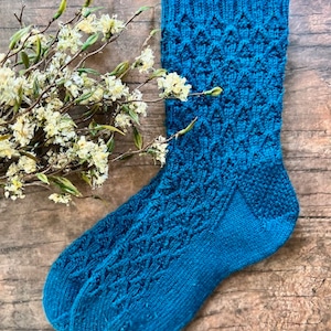 May include: A pair of teal blue knitted socks with a geometric pattern.