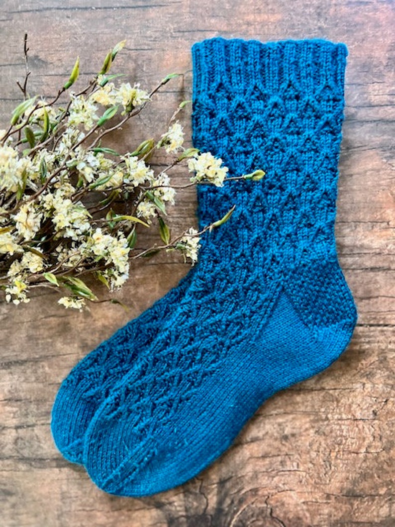 May include: A pair of teal blue knitted socks with a geometric pattern.