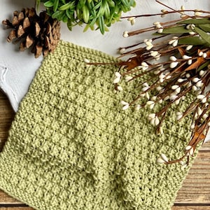 Può includere: Un canovaccio di maglia verde con un motivo testurizzato. Il canovaccio è realizzato con un filato morbido e assorbente, perfetto per pulire schizzi e disordine in cucina.