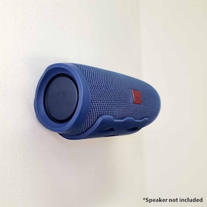 Könnte beinhalten: Ein blauer zylindrischer Lautsprecher an einer weißen Wand montiert. Der Lautsprecher hat eine netzartige Textur und einen dunkelblauen kreisförmigen Lautsprecher an einem Ende. Ein kleines rotes Quadrat ist an der Seite sichtbar. Der Text "Speaker not included" steht unten.